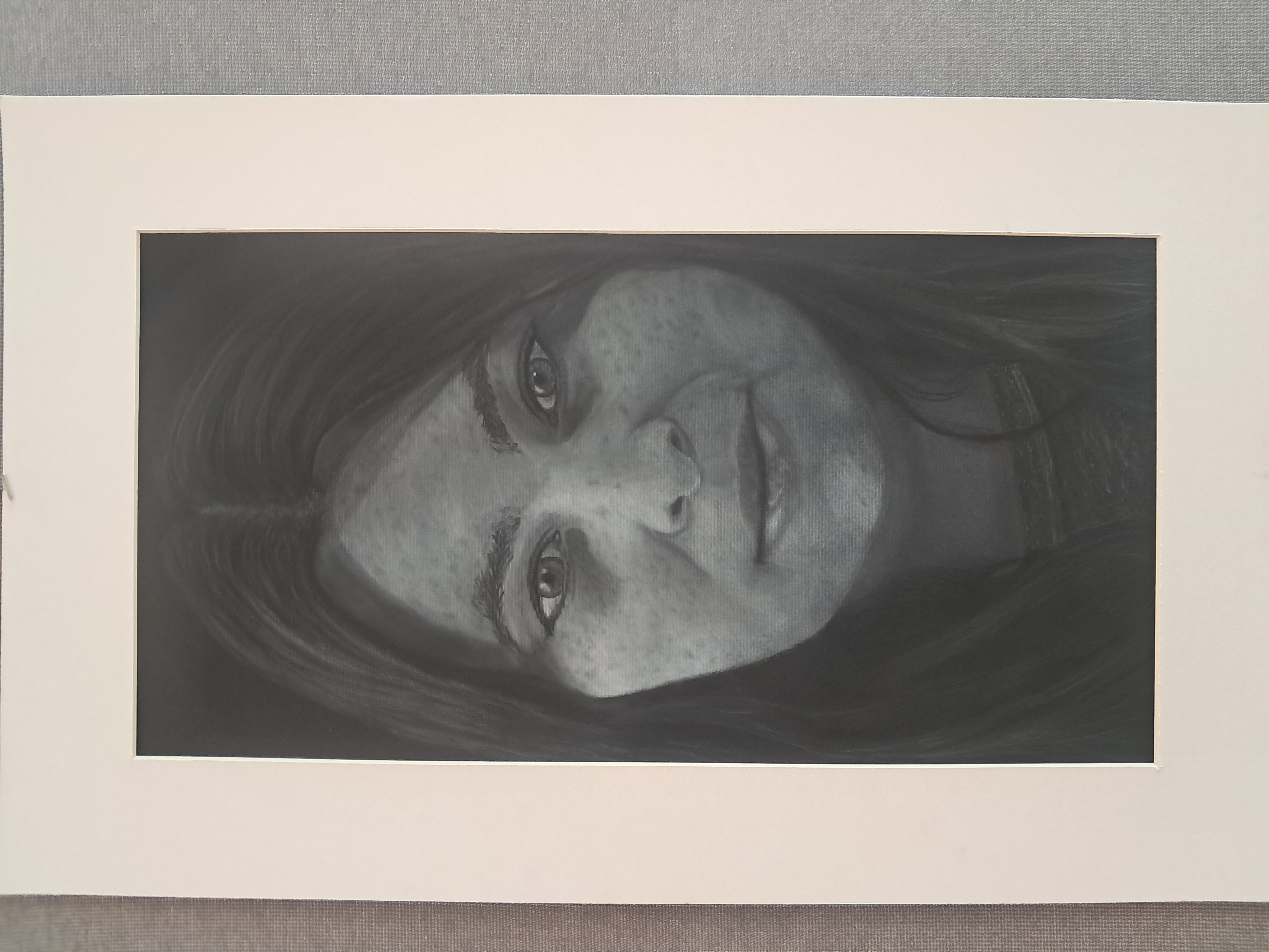 Charcoal self-portrait drawing on black paper.